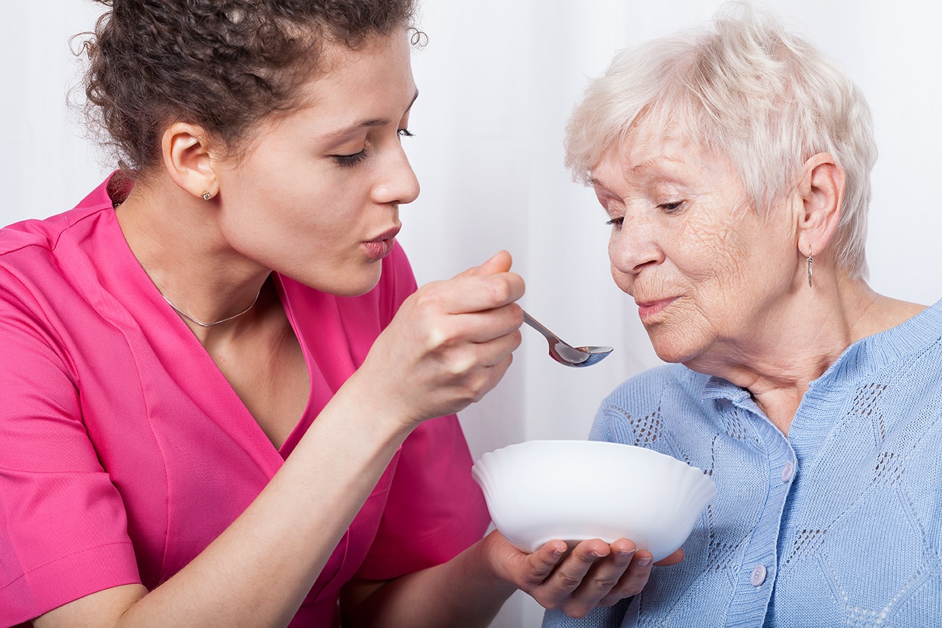 aide à domicile qui nourrit une personne âgée